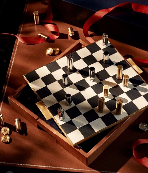 A high-end, top-down shot of a metallic chess set on a dark, elegant surface with ribbon accents and controlled studio lighting.