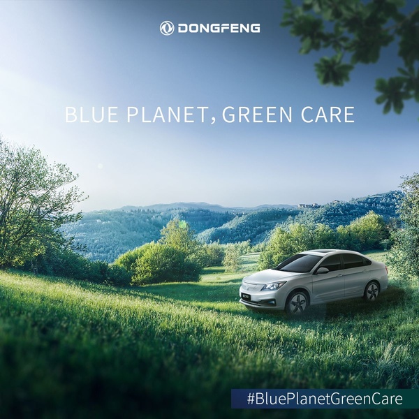 A high-quality, wide-angle shot of a modern sedan parked in a lush, green natural landscape under a bright, clear sky.