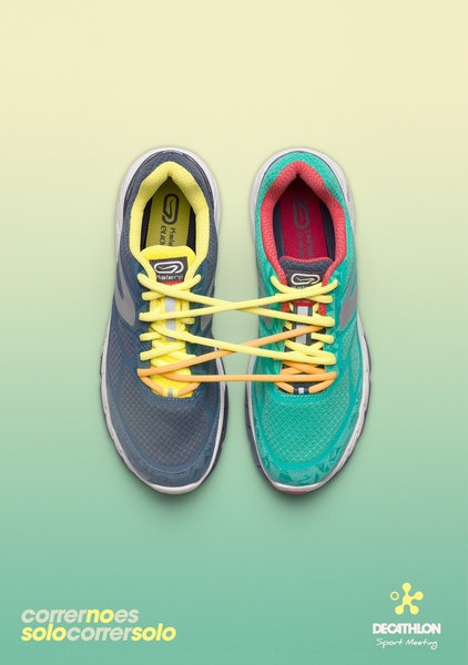 A minimalist overhead shot showing two running shoes linked by their shoelaces, emphasizing unity and movement on a clean gradient background.