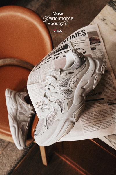 A refined, lifestyle-oriented still life shot featuring a running shoe resting on an open newspaper, bathed in warm, natural lighting.