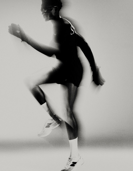 A high-contrast, black and white photograph featuring a runner in mid-stride with motion blur to emphasize speed and athletic performance.