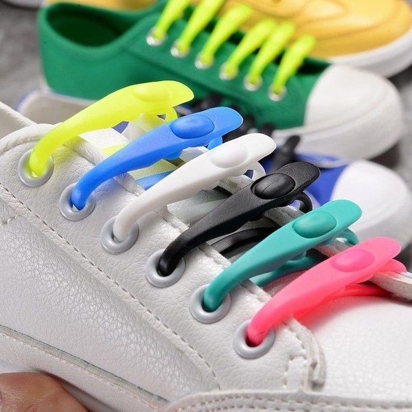 A close-up, high-contrast shot demonstrating the installation and final look of colorful, elastic no-tie shoelaces on a white sneaker.