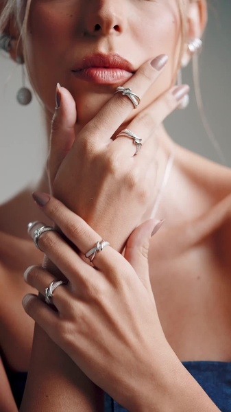 A close-up shot focusing on hands adorned with multiple minimalist silver rings, set against a neutral, clean background.