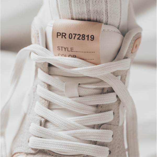 A tightly framed, high-contrast close-up of a running shoe focusing on texture, material quality, and brand-like detailing.