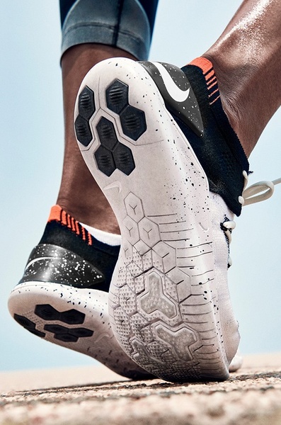 A close-up, low-angle shot focusing on the high-tech tread and design details of a running shoe while the athlete is in motion.