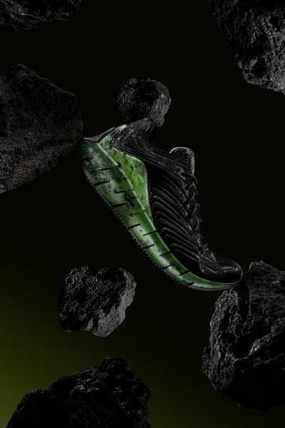 A sleek black running shoe with neon green accents is suspended among floating dark volcanic rocks against a deep black background.