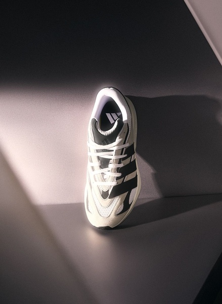 A high-end product-focused shot of a running shoe using dramatic, directional studio lighting against a clean, geometric background.