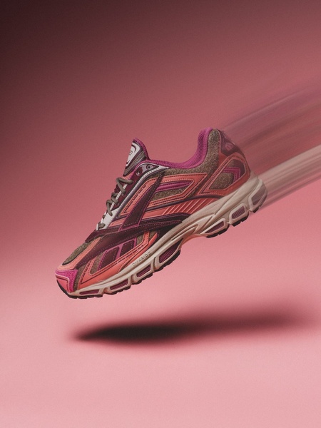 A high-performance Running Shoe is centered against a soft pink background with a digital motion-blur effect suggesting rapid movement.