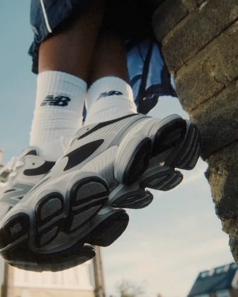 A close-up, low-angle shot of a runner showcasing the tread and heel design of their footwear while sitting on a ledge.