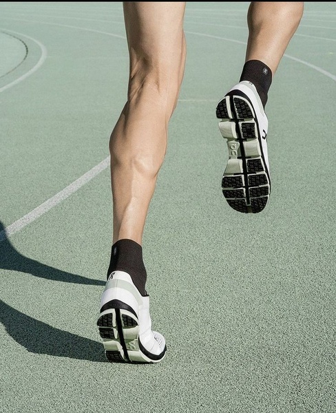 A close-up, motion-focused shot of a runner's legs on an athletic track, highlighting the product design and athletic capability.