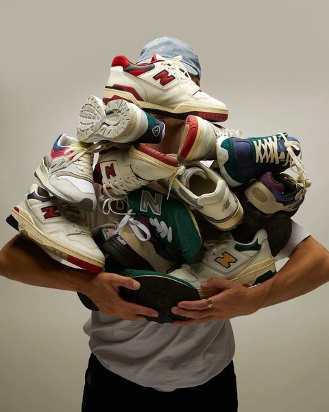 A striking product-focused image featuring a person holding a large, overflowing stack of various running shoes, emphasizing brand variety and abundance.