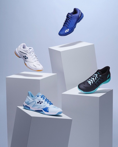 A high-end, studio-lit display featuring four distinct athletic shoe models arranged on geometric pedestals against a soft blue gradient background.