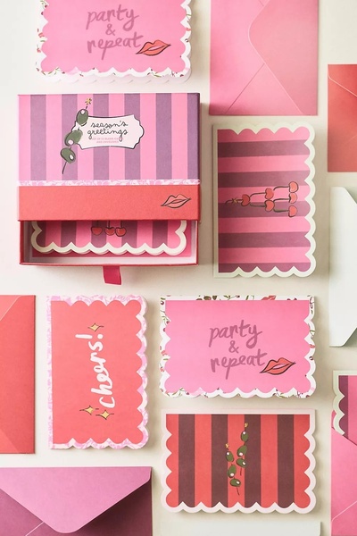 A high-angle flat lay view showing multiple stationery set cards, envelopes, and a branded storage box with a festive color palette.