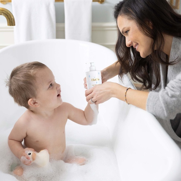 A close-up shot of a mother applying moisturizer to her baby during bath time, emphasizing a tender, safe, and nurturing moment.