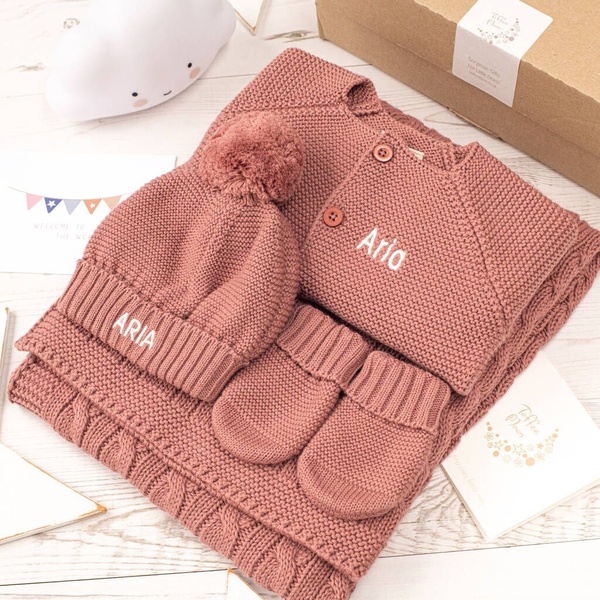 baby clothing set, personalized baby gift, knitted baby outfit, baby gift box, infant clothing set, gift guide, flat lay, minimalist, calm, warm, pink, neutral