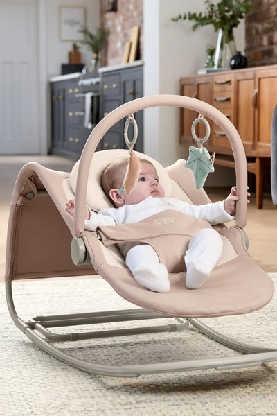 A high-quality lifestyle shot featuring a baby in a minimalist bouncer, emphasizing comfort and neutral design in a home environment.