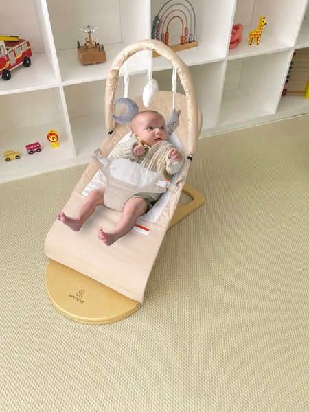 A high-angle product shot showcasing a baby bouncer in a bright, organized nursery, emphasizing aesthetic appeal and product integration.