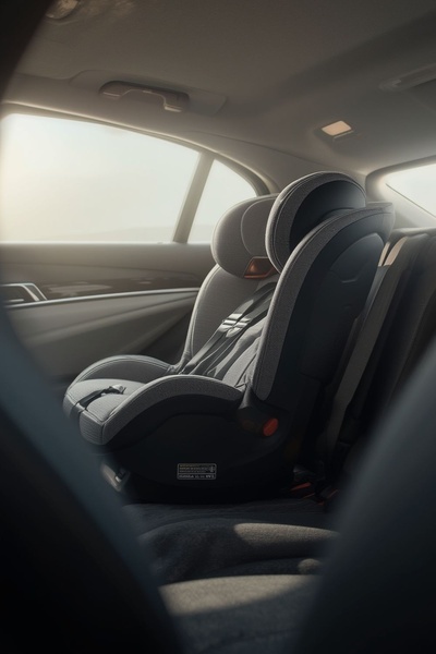 A high-quality, static image of a car seat positioned in the backseat of a luxury vehicle, focusing on design and safety aesthetics.