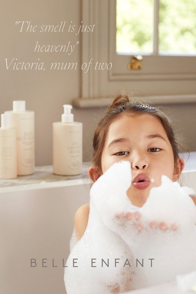 A soft-lit, 2_3 aspect ratio image featuring a child playing with soap foam while highlighting the brand's baby wash bottles.
