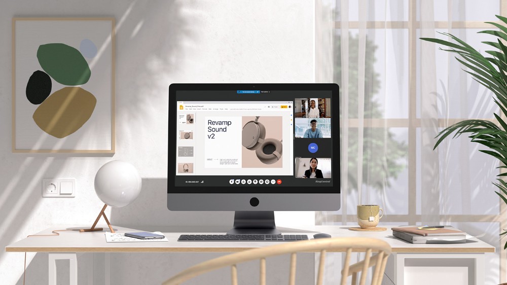 A high-quality 16:9 lifestyle shot showing a clean, organized office desk with a computer displaying a video conference featuring product information.