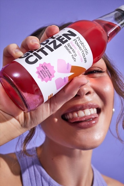 A close-up shot featuring a person holding a bottle of sparkling water kefir, creating an immediate, personal connection with the product.