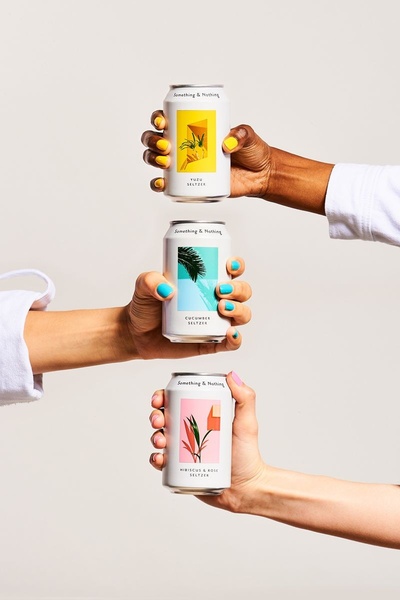 A vertical composition featuring three hands holding different flavors of seltzer, utilizing distinct color blocks and minimalist packaging.