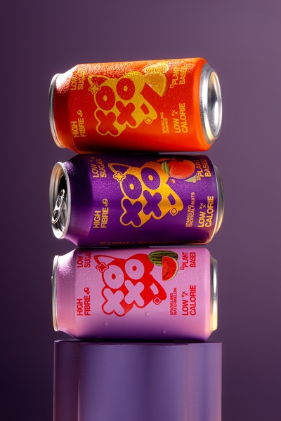 A vertical, studio-style shot showcasing three flavors of sparkling fruit drinks in a vibrant, color-coordinated stack against a minimalist background.