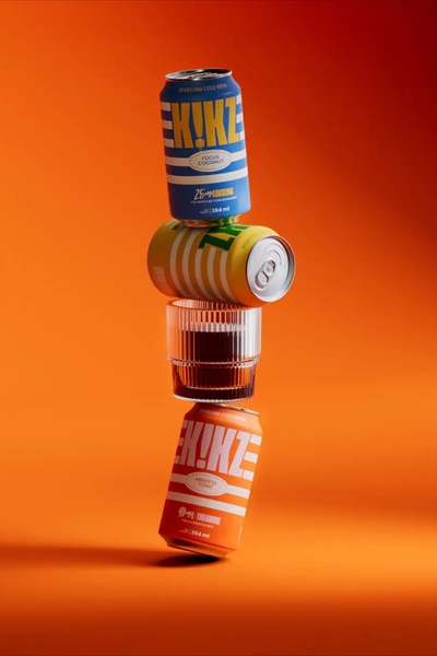 A vertical, balanced stack of beverage cans and a glass, captured in a clean studio setting with vibrant, uniform color branding.