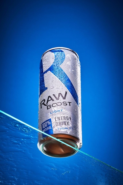A high-definition macro shot of an energy drink can featuring condensation and a glass surface on a vibrant blue background.