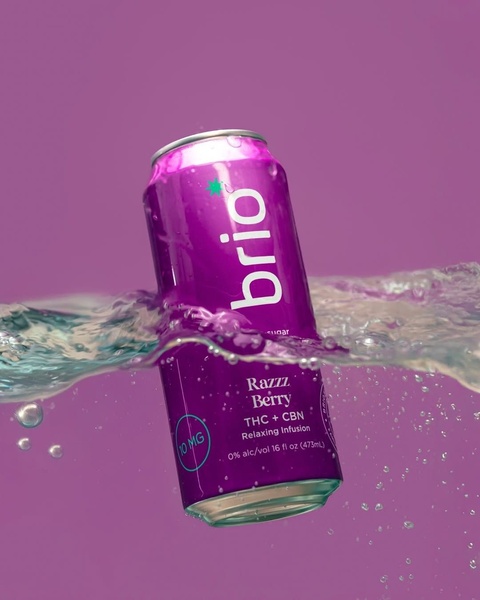 A high-quality product hero shot featuring a can of Brio Razzz Berry THC and CBN infusion submerged in water against a bold violet background.