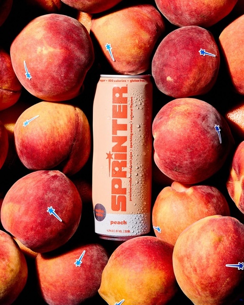 A crisp, high-contrast hero shot of a peach vodka soda can surrounded by fresh peaches, utilizing a cohesive color palette.
