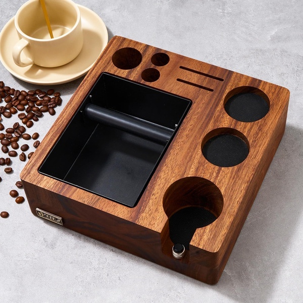 A high-quality, top-down perspective of a wooden coffee knock box station placed next to a cup and fresh coffee beans on a minimalist stone surface.
