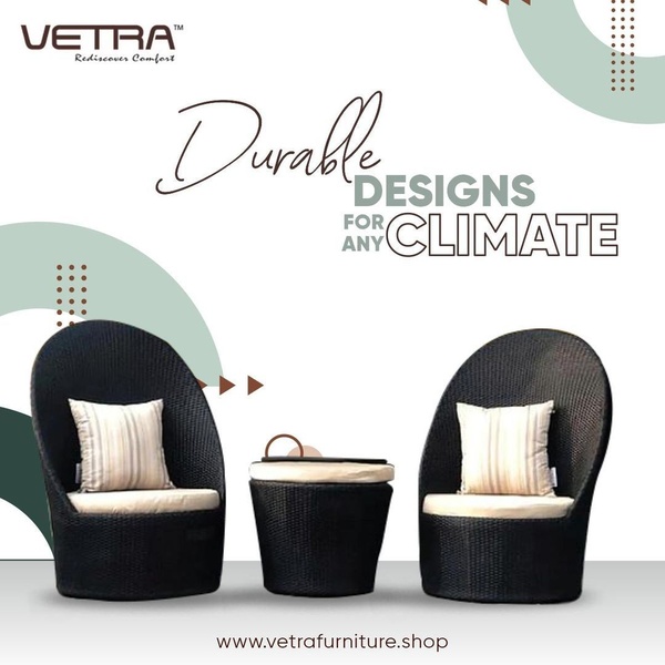 A square-format ad featuring two dark wicker chairs and a matching side table against a clean white background with abstract graphic overlays.