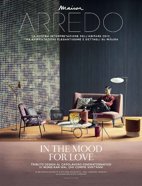 A sophisticated, cinema-inspired advertisement featuring a man sitting on a sofa in a modern, stylishly decorated living room.
