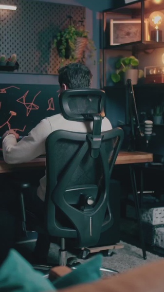 A high-quality, professional image showing a person working at an ergonomic office chair, set in a cozy, well-lit workspace with a focus on interior design.