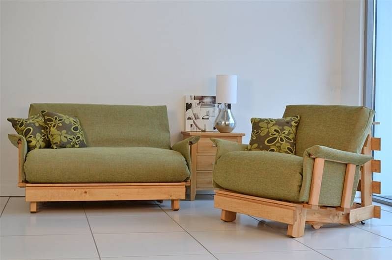 This creative displays a sage green futon sofa paired with a matching armchair in a clean, bright studio environment.