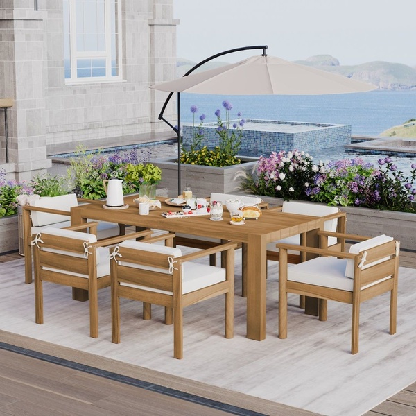 A clean, bright lifestyle shot of a wooden dining table and chairs set on a luxury patio overlooking the ocean.