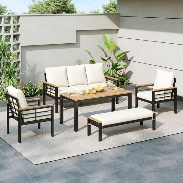 A high-quality, balanced lifestyle shot of a modern outdoor furniture set placed in a sunlit, minimalist courtyard setting.