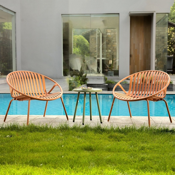 A clean, symmetrical product shot featuring two orange patio chairs and a small table set against a modern architectural background and blue pool.