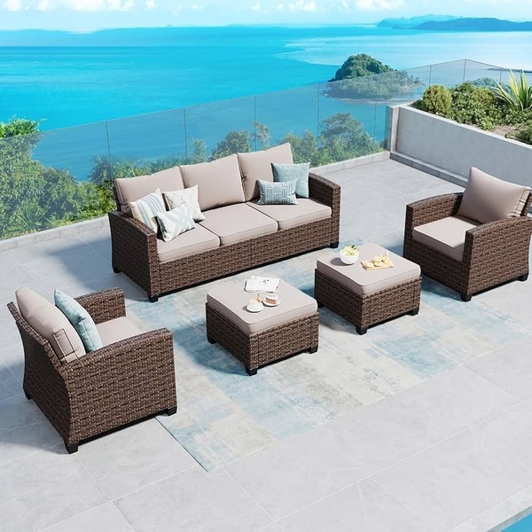 A high-angle, clean shot of a complete patio furniture set arranged on a balcony overlooking a scenic ocean view, focusing on lifestyle appeal.