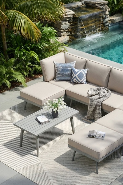 An overhead, high-angle shot of a modern outdoor sectional sofa arranged by a backyard pool, featuring neutral tones and elegant accessories.