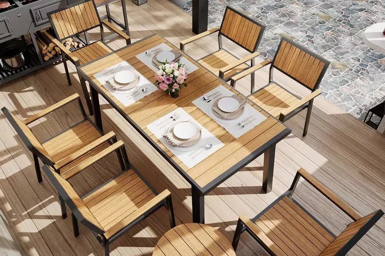 A high-angle shot of a premium wood and metal patio dining table with place settings, emphasizing lifestyle and quality construction.