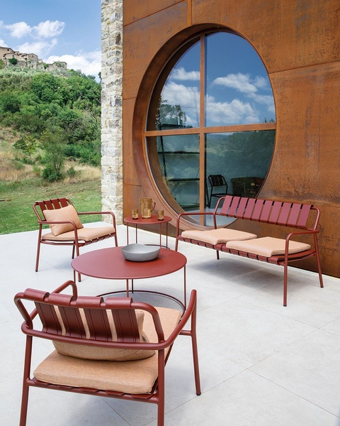 A high-end outdoor furniture set is artfully arranged on a clean, modern patio overlooking a rustic landscape, emphasizing design harmony.