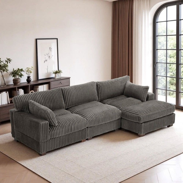 A high-quality lifestyle shot of a grey corduroy sectional sofa in a neutral-toned, sunlit room, focusing on texture and interior design.
