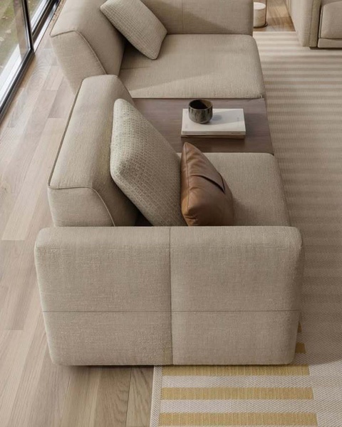A high-angle, clean product shot of a beige sectional sofa with a wooden side table, focusing on interior design aesthetic.
