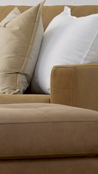 A close-up aesthetic shot of a premium leather sofa featuring soft, high-contrast cushions to emphasize comfort and quality materials.