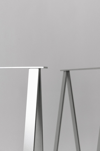 A high-contrast, clean-focus studio shot showcasing the architectural structure of premium metal table legs against a neutral background.