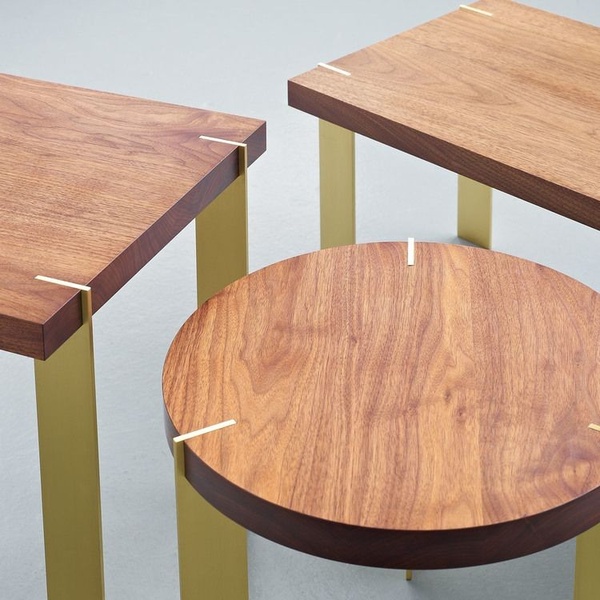 A top-down, clean product photography shot highlighting the wood grain and brass joints of high-end nesting tables.