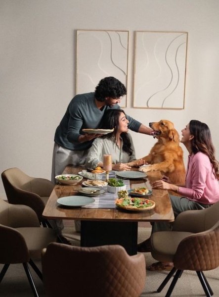 This ad creative features a young couple sharing a meal with their dog at a modern dining table, emphasizing a warm and inviting home atmosphere.