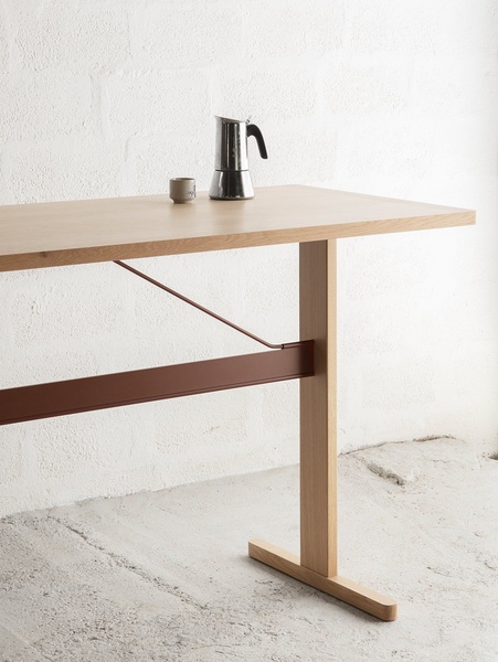 A high-end, clean product hero shot featuring a minimalist desk set against a textured white wall, focusing on material contrast.